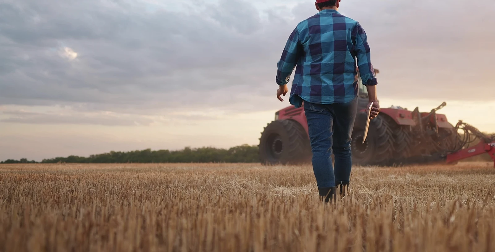 farmer with a tablet walking towards his tractor